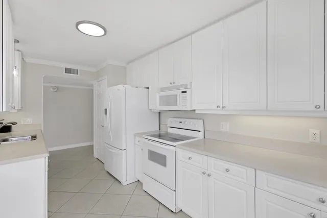 a kitchen with white cabinets and white appliances