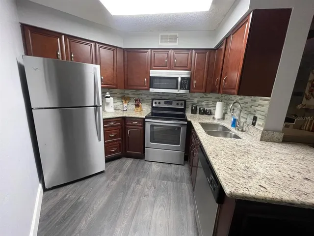 a kitchen with granite countertop a refrigerator a sink a stove a microwave and island