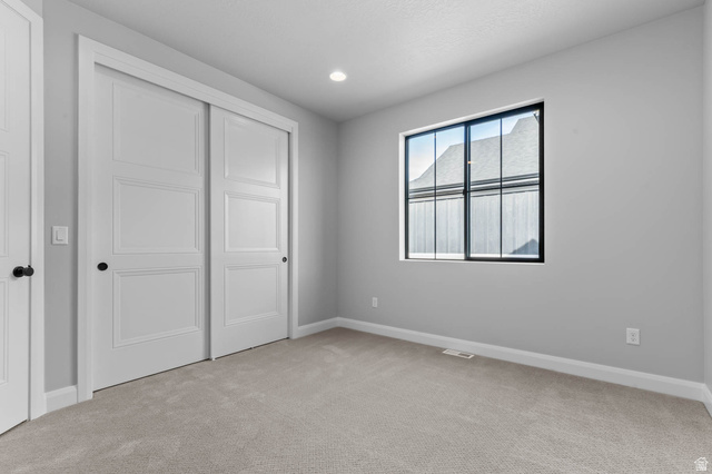 11673 South Halls Crk Road Draper, UT 84020 - Photo 14 of 22 Recessed lighting illuminates a space featuring light gray walls, plush carpeting, a black-framed window, and white sliding closet doors with black hardware