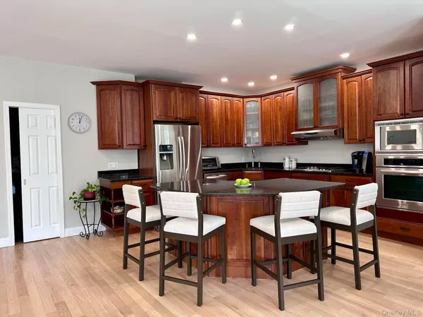 a kitchen with stainless steel appliances kitchen island granite countertop a table chairs and a refrigerator