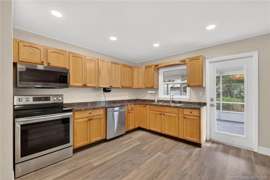 607 Southeast Cortez Avenue Stuart, FL 34994 - Photo 11 of 29 a kitchen with granite countertop wooden floors stainless steel appliances and sink