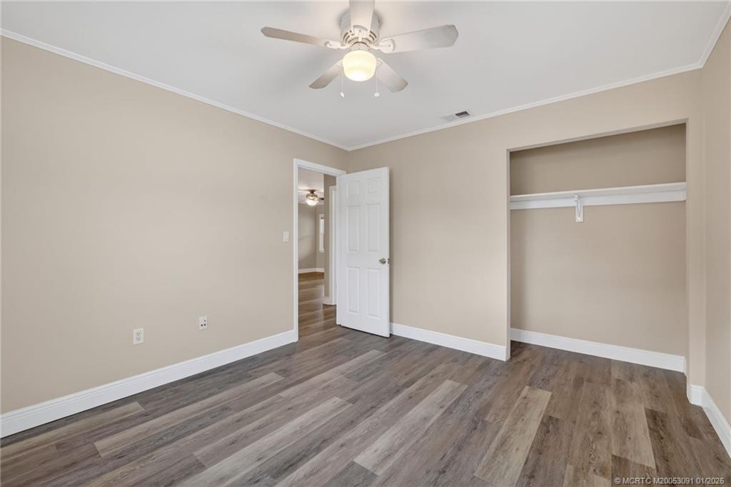 607 Southeast Cortez Avenue Stuart, FL 34994 - Photo 15 of 29 an empty room with wooden floor a ceiling fan and closet