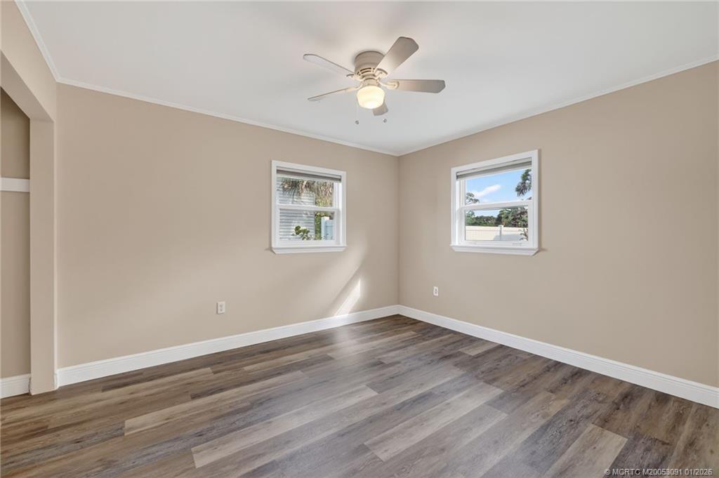 607 Southeast Cortez Avenue Stuart, FL 34994 - Photo 18 of 29 a view of an empty room with wooden floor and a ceiling fan