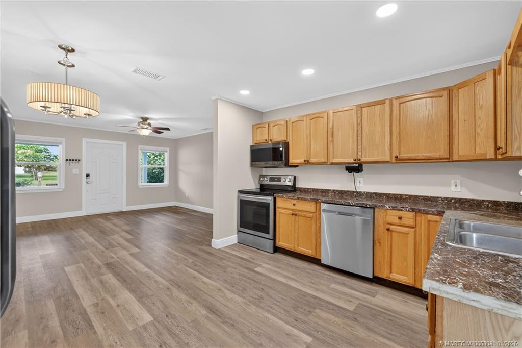 607 Southeast Cortez Avenue Stuart, FL 34994 - Photo 8 of 29 a kitchen with granite countertop wooden floors a sink stainless steel appliances and cabinets