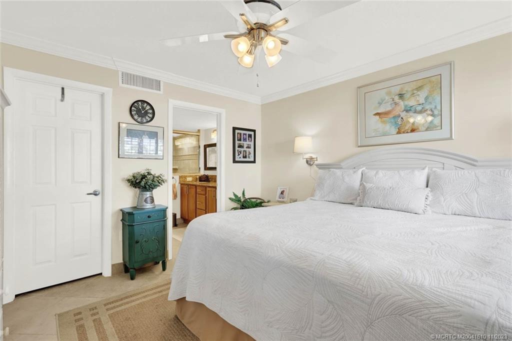 1950 Southwest Palm City Road, Unit 4107 Stuart, FL 34994 - Photo 28 of 65 a spacious bedroom with a bed and a chandelier