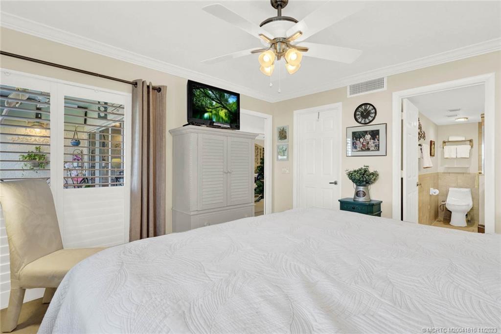 1950 Southwest Palm City Road, Unit 4107 Stuart, FL 34994 - Photo 29 of 65 a bedroom with a large bed and a chandelier