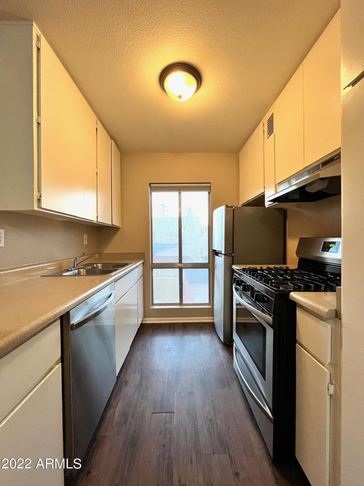 1701 West Tuckey Lane, Unit 225 Phoenix, AZ 85015 - Photo 4 of 13 a kitchen with stainless steel appliances granite countertop a stove a sink and a refrigerator