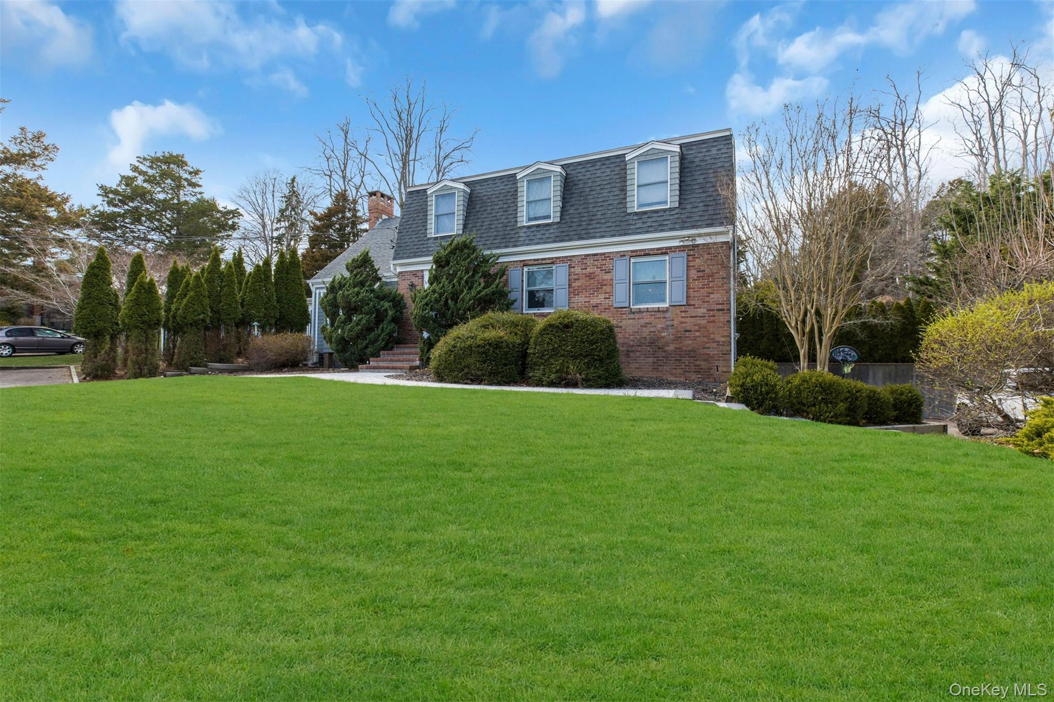 345 Colonial Road Southold, NY 11971 - Photo 5 of 43 a front view of a house with garden and trees