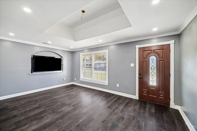 a view of an empty room with wooden floor and a window