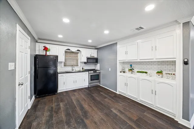 a kitchen with stainless steel appliances a refrigerator and white cabinets
