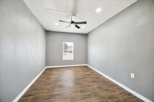 an empty room with windows and ceiling fan