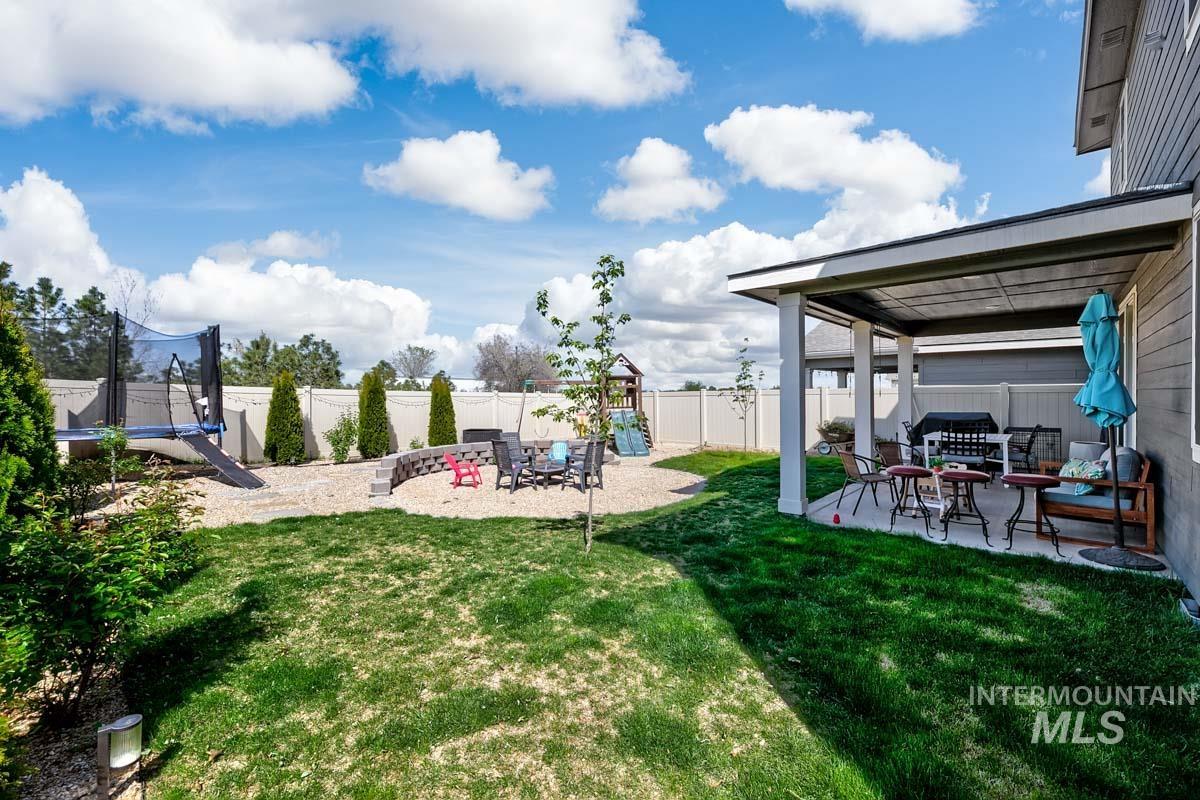 4469 South Colditz Way Meridian, ID 83642 - Photo 27 of 30 Manicured backyard with a covered patio, a rock-landscaped area with a retaining wall, and a full privacy fence