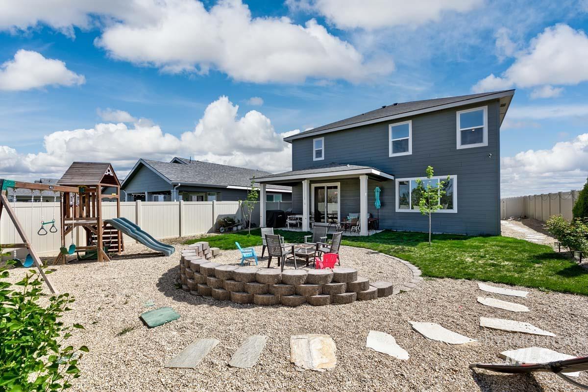 4469 South Colditz Way Meridian, ID 83642 - Photo 28 of 30 Expansive backyard featuring a covered patio, gravel landscaping, and a tiered stone retaining wall surrounding a fire pit area