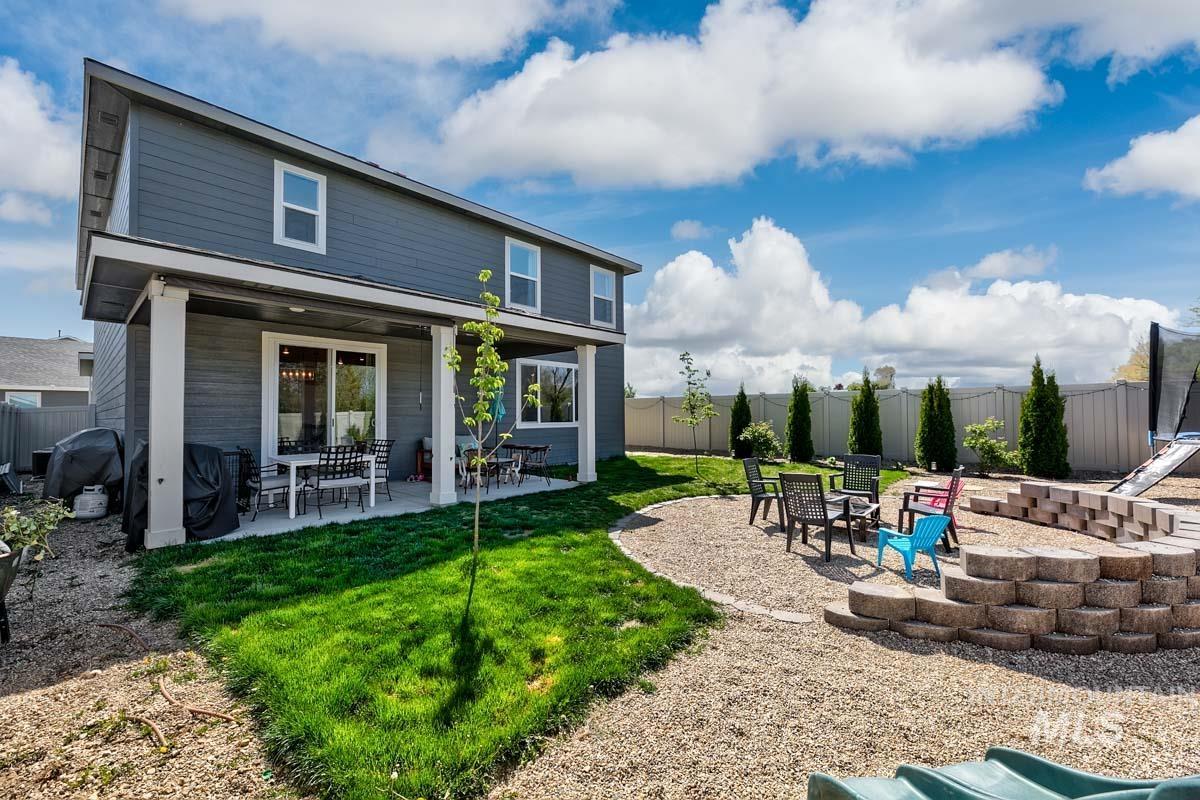 4469 South Colditz Way Meridian, ID 83642 - Photo 29 of 30 Expansive backyard featuring a covered patio, gravel fire pit area with tiered block seating, and a manicured lawn