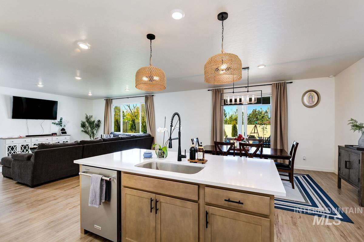 4469 South Colditz Way Meridian, ID 83642 - Photo 8 of 30 Open-concept living space featuring wood-finish flooring, recessed lighting, and a kitchen island with a stainless steel sink and a white countertop