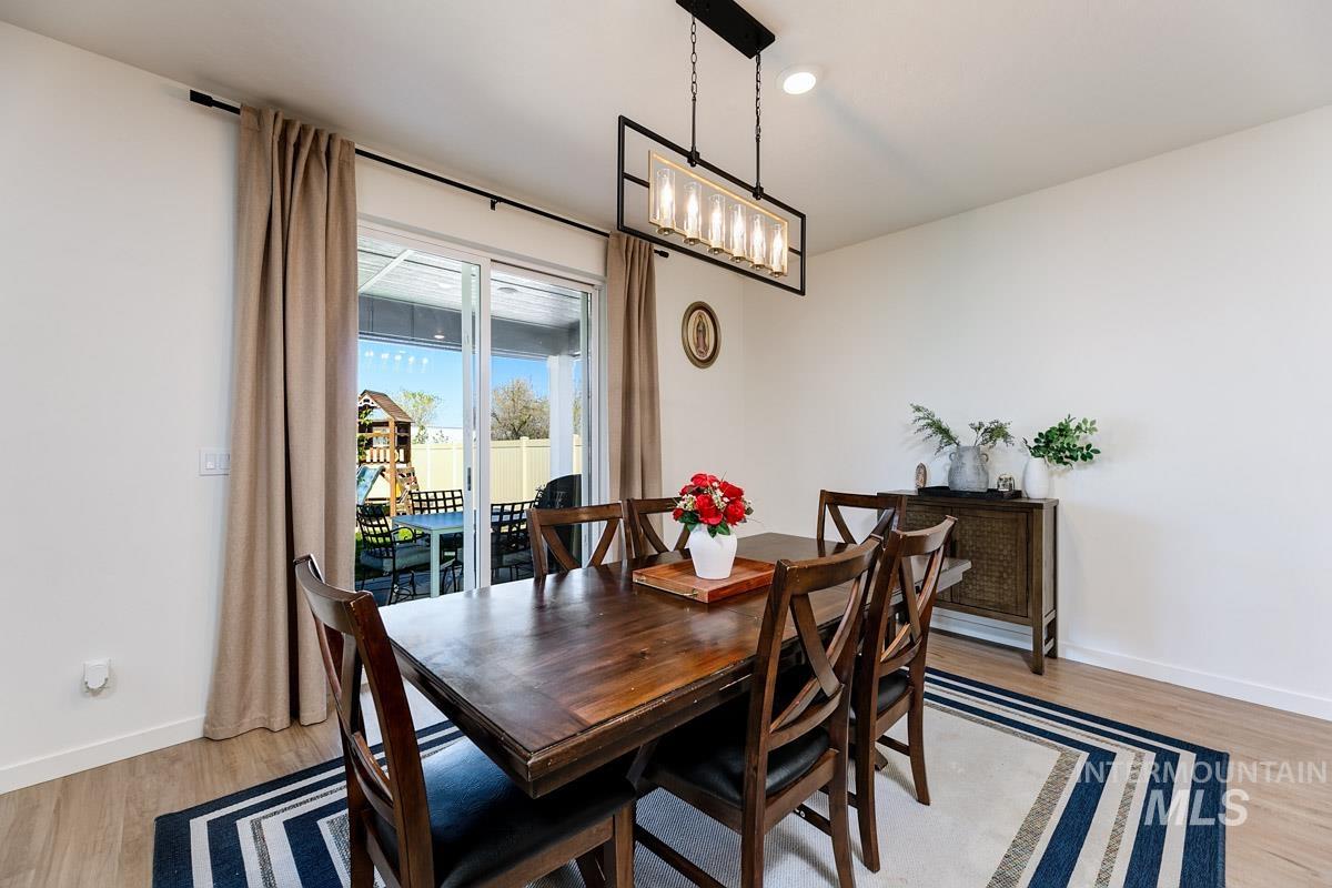 4469 South Colditz Way Meridian, ID 83642 - Photo 9 of 30 Well-lit interior space featuring wood-finish flooring, a contemporary linear chandelier, and white wall finishes