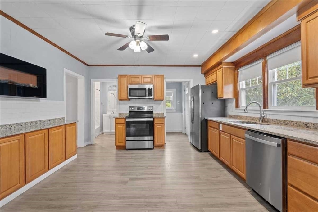 131 South Main Street Clinton, MA 01510 - Photo 14 of 36 a large kitchen with stainless steel appliances granite countertop a stove top oven a sink dishwasher a dining table and chairs with wooden floor