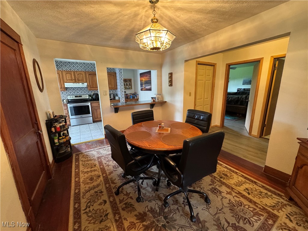 71322 Sharon Road Bridgeport, OH 43912 - Photo 13 of 39 Dining space featuring dark wood finished floors, a textured ceiling, and a chandelier