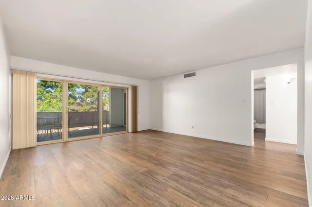 a view of an empty room with wooden floor and a window