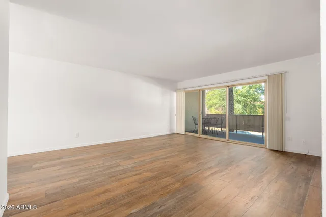 a view of an empty room with wooden floor and a window