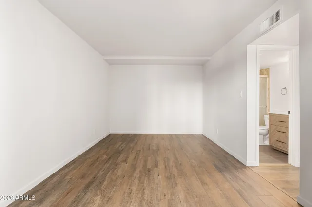 an empty room with wooden floor and bathroom