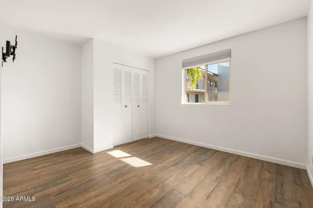 an empty room with wooden floor and windows