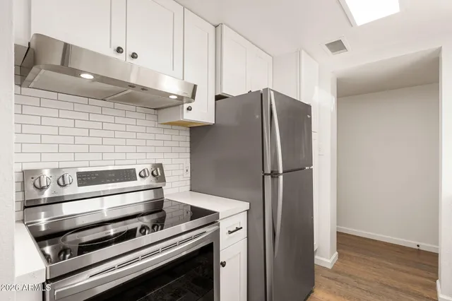 a kitchen with metallic refrigerator and wooden floor