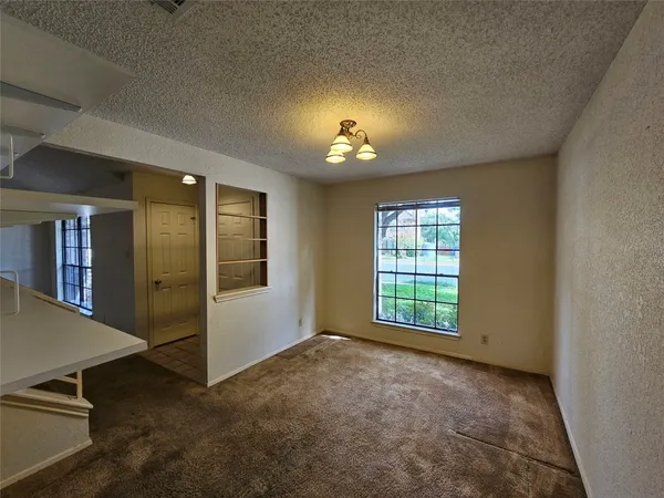 an empty room with windows and chandelier fan