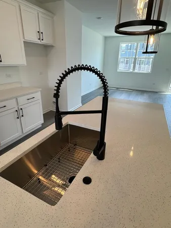 a white kitchen with granite countertop a stove and a sink