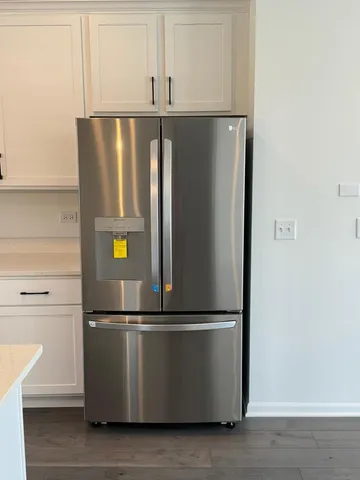 a large kitchen with stainless steel appliances granite countertop a stove a sink dishwasher and a refrigerator with wooden floor