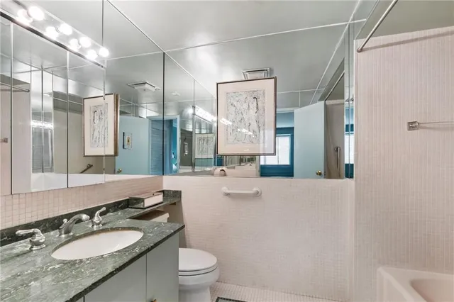 a bathroom with a granite countertop sink toilet a mirror a vanity and shower