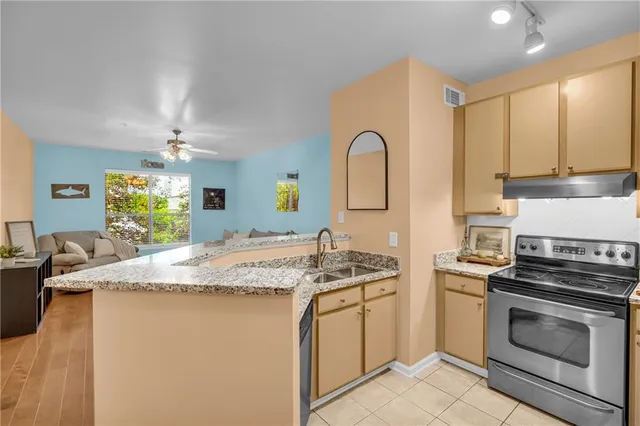a kitchen with stainless steel appliances granite countertop a sink a stove a refrigerator cabinets and a dining table