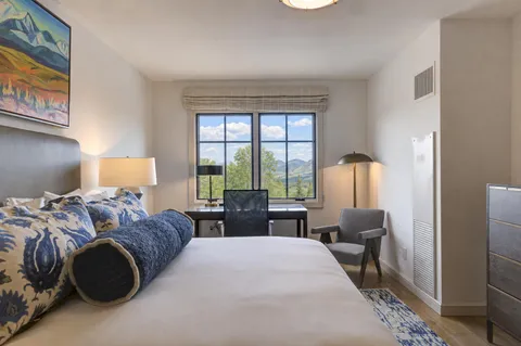 a bedroom with a bed wooden floor and a large window