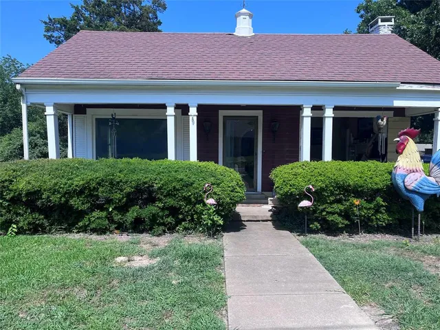 a front view of a house with a yard and potted plants