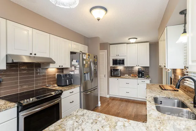 a kitchen with granite countertop a stove a sink and a refrigerator