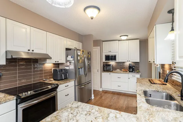 a kitchen with granite countertop a stove a sink and a refrigerator