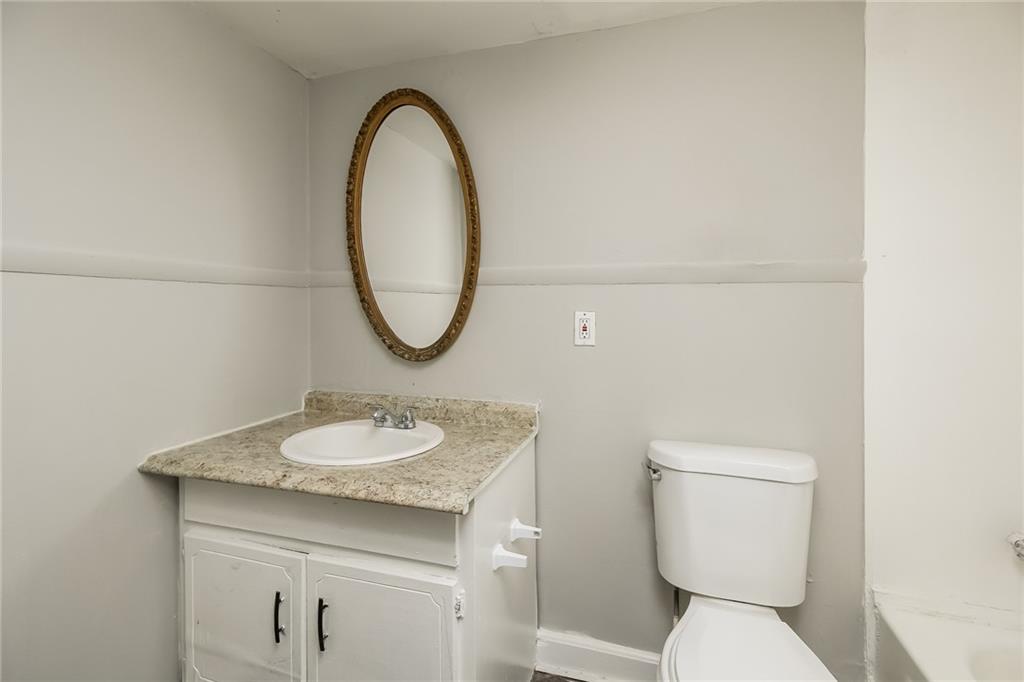 3864 McGill Lane Decatur, GA 30034 - Photo 22 of 25 a bathroom with a granite countertop toilet a sink and a mirror