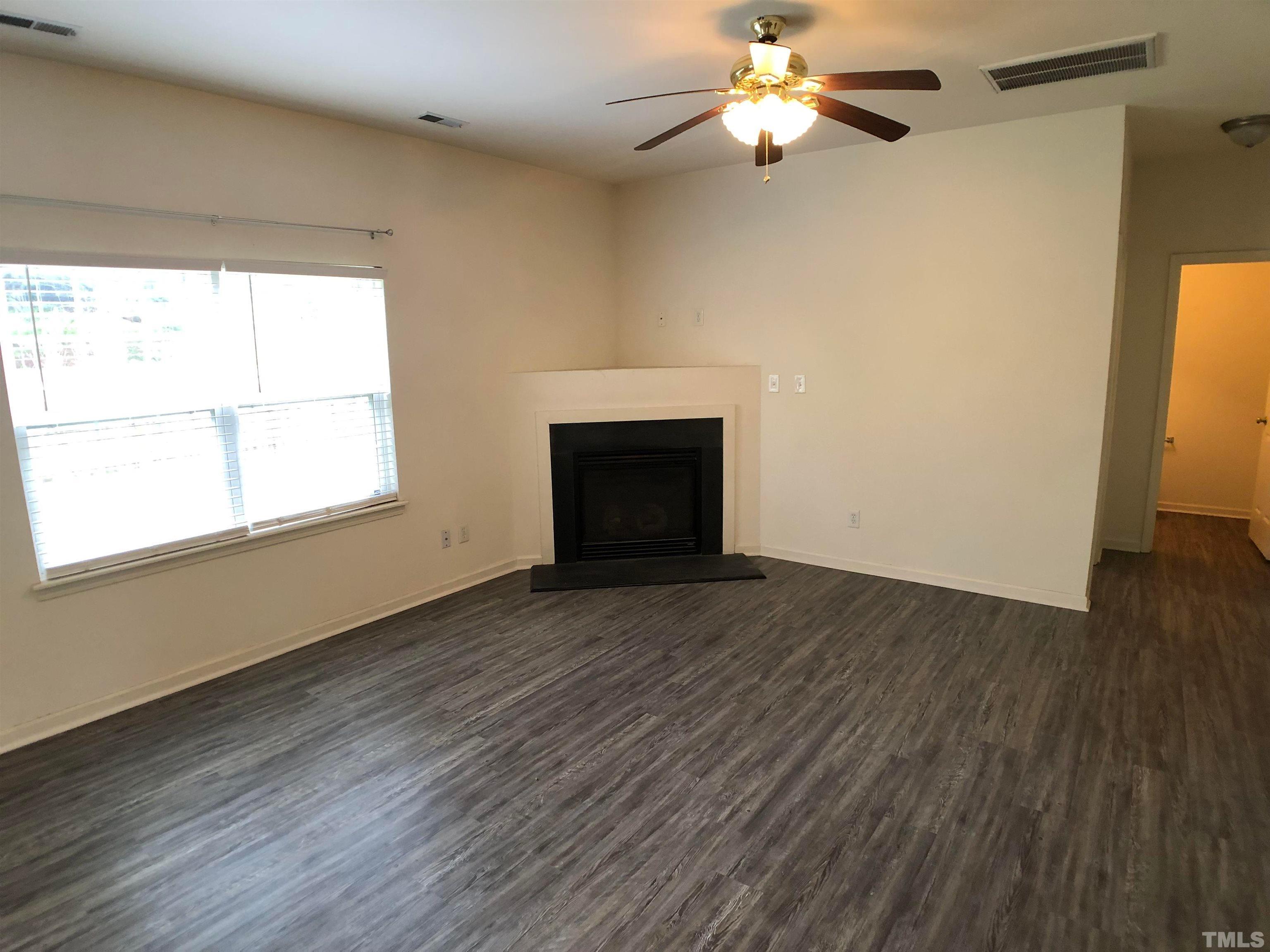 405 Hanson Road Durham, NC 27713 - Photo 11 of 27 a view of an empty room with wooden floor fireplace and a window