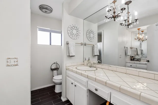 a bathroom with a granite countertop sink mirror and toilet