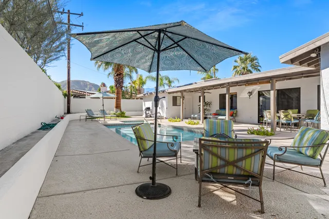 a view of a patio with table and chairs under an umbrella
