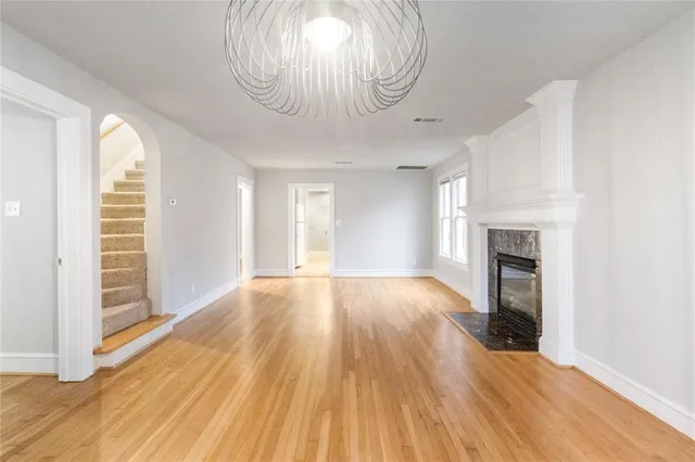 an empty room with wooden floor fireplace and windows