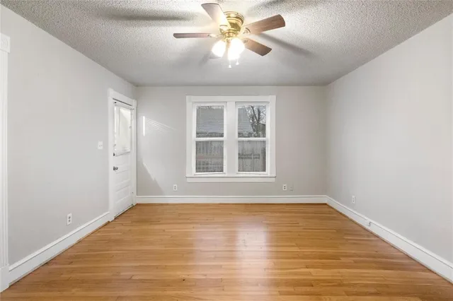 a view of an empty room with window and chandelier fan