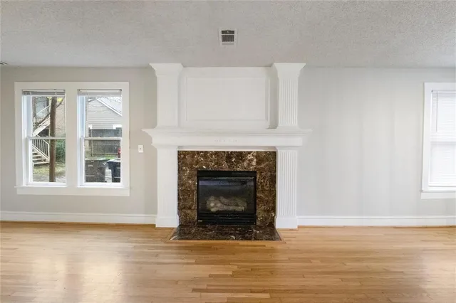 a view of an empty room with wooden floor and a fireplace