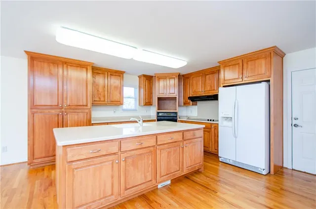 a kitchen with stainless steel appliances granite countertop a refrigerator a sink dishwasher and wooden cabinets with wooden floor