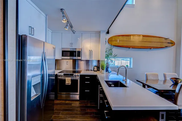 a kitchen with stainless steel appliances a stove a refrigerator and a dining table