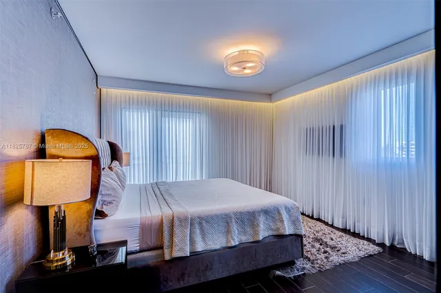 a bed sitting in a spacious bedroom next to a lamp