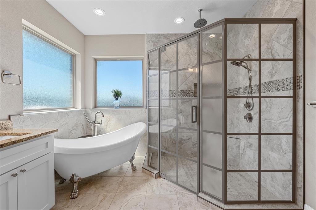 23 Independence Trail Waco, TX 76708 - Photo 19 of 35 Freestanding clawfoot tub with a floor-mounted faucet, complemented by a walk-in shower featuring a grid-patterned glass enclosure and dual shower heads