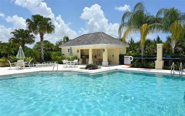 a view of a swimming pool with lawn chairs under an umbrella