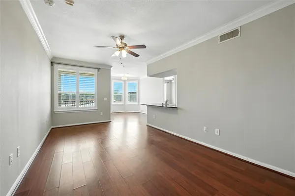 a view of an empty room with a window and wooden floor