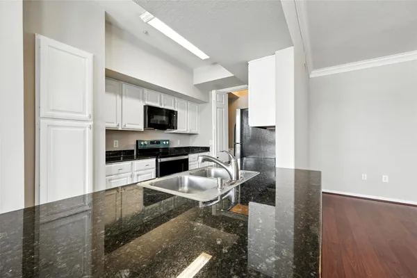 a kitchen with granite countertop a stove refrigerator and microwave